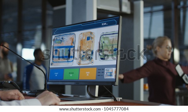 Anonymous man at checkpoint in airport exploring\
luggage on screen with\
x-ray.