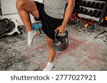 Anonymous man performs Single Leg Balance With Weight, using a kettlebell. Hardcore gym setting.