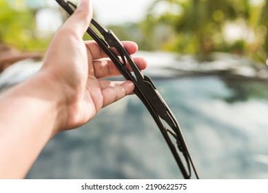 An Anonymous Man Raises The Windshield Wipers To Clean The Front Windscreen. Car Cleaning And Maintenance Done Outside In The Morning.