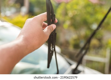 An Anonymous Man Raises The Windshield Wipers To Clean The Front Windscreen. Car Cleaning And Maintenance Done Outside In The Morning.