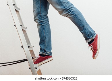 Anonymous man reaching on top of ladder climbing, indoors studio people shot.