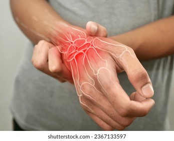 Anonymous person touching his wrist, suferring from arthritis disease, close up against grey background