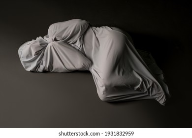 Anonymous person wrapped in cloth lying on floor