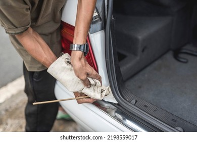 Anonymous Photo Of A Mechanic Cleaning The Grooves Of The Car Trunk Rubber Weatherstripping With A Stick Wrapped With Microfiber Towel. At A Auto Repair Shop.