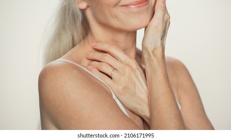 Anonymous Senior Woman Touching Her Neck, Chest, With Hands, Enjoying Soft Skin. Elderly Female Natural Beauty. Dignity And Grace In Old Age. Isolated Background For Skin Care, Healthy Living Concept