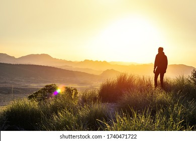 Anonymous silhouette of a man at mountain top against a foggy landscape. First man in another world. Concept of another planet discovering a new land. Copy space.