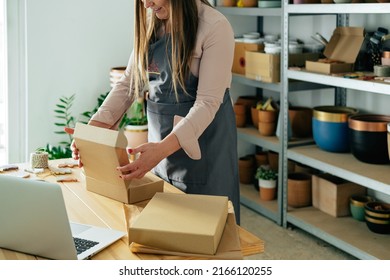 An Anonymous Smiling Woman Preparing Christmas Ornaments Of Clay For Delivery At Her Store