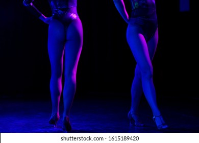 Anonymous stripper show. Legs of two sexy dancers in fishnet stockings. Strippers or cabaret pole dancers at a stage in a strip club or erotic striptease show.