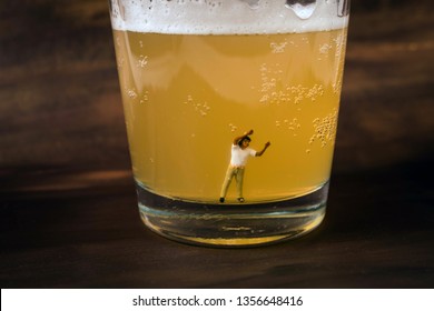 Anonymous, unrecognizable miniature man in a glass of beer. Binge drinking concept. Tiny person with a drinking problem at a crazy party. Last call, or time to seek help with a drinking problem. 