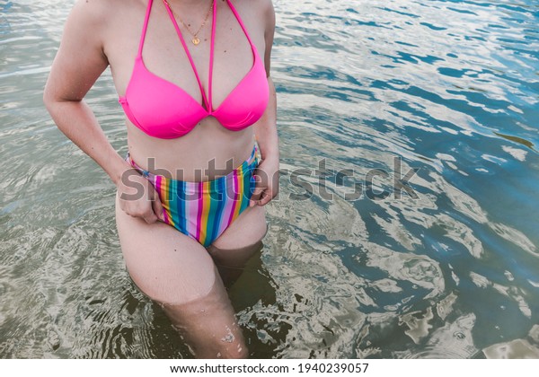 An\
anonymous woman adjusts her bikini bottom in almost waist deep\
water. Vacation getaway and summer fashion\
theme.