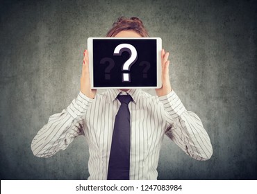 Anonymous woman covering face with tablet showing question mark hiding personality in Internet