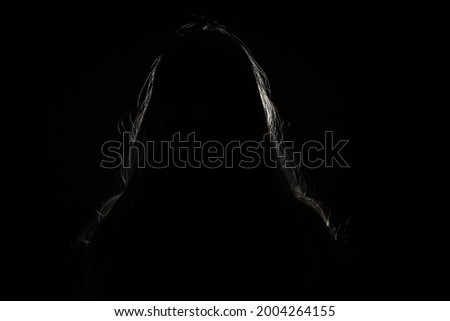 anonymous woman hiding face and identy in the dark shadow