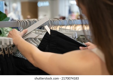 Anonymous Woman Inspecting Pants On Rack