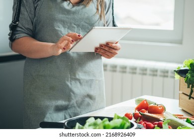 An Anonymous Woman Making Healthy Lunch With Fresh Colorful Vegetables At The Kitchen Table While Reading Recipe Online On Her Tablet