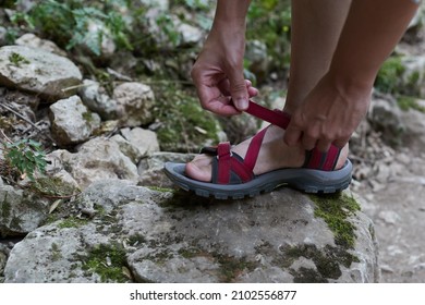 Anonymous Woman Tying Her Sandals On A Rocky Area