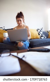 Anonymous Woman Working On Laptop On Sofa Whilst Drinking Coffee.