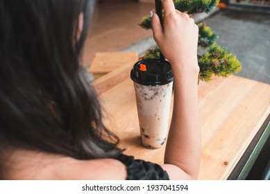 An Anonymous Young Lady With Her Order Of A Large Bubble Tea In A Simple Plastic Takeaway Cup. At A Milk Or Boba Tea Cafe Store.