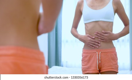 Anorexia Concept - Slim Teen Girl, With Protruding Ribs Looking At Her Reflection In The Mirror