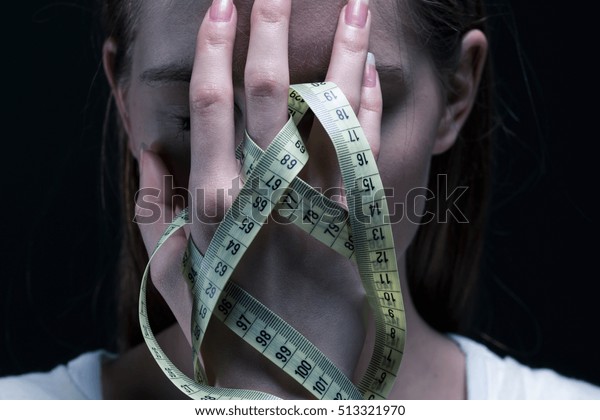 Anorexic girl\
covering her face with a\
centimeter