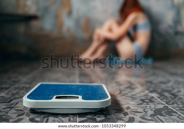Anorexic woman\
sitting on the floor, weight\
loss