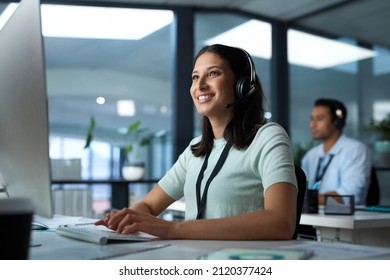 Another day, another happy client. Shot of a young woman using a headset and computer in a modern office. - Shutterstock ID 2120377424