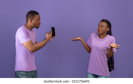 Another Life Online, Cheating Concept. Angry Black Man Checking His Girlfriend Mobile Phone, Showing Provocative Messages And Asking For Explanation, Lady Spreading Hands, Violet Studio Background