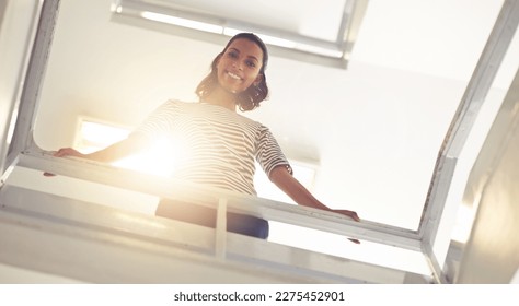 Another step up the ladder of success. Low angle portrait of a young businesswoman standing in a stairwell.