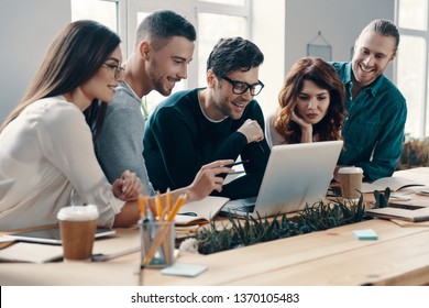 Another working day. Group of young modern people in smart casual wear using modern technologies while working in the creative office