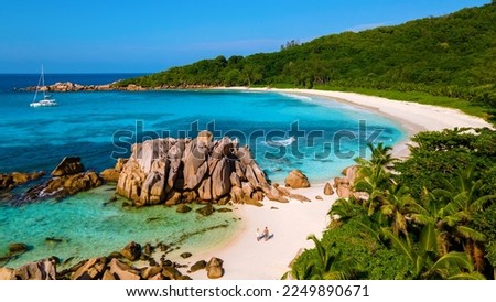 Anse Cocos beach, La Digue Island, Seychelles, Drone aerial view of La Digue Seychelles bird eye view.of tropical Island, couple men, and woman walking at the beach during sunset at a luxury vacation