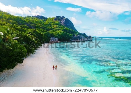 Anse Source d'Argent beach, La Digue Island, Seychelles, Drone aerial view of La Digue Seychelles bird eye view. of tropical Island, couple men, and woman walking at the beach during sunset