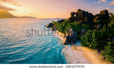 Anse Source d'Argent La Digue Seychelles, a couple of Caucasian men and Asian women on a tropical beach during a luxury vacation in Anse Source d'Argent La Digue Seychelles