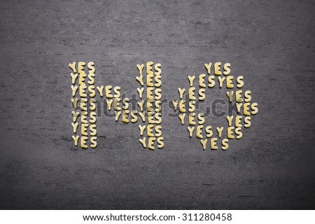 The answer  "no" made up of a set of words "yes", with small pasta letters on a dark background of a wooden board, showing the hidden meaning and ambiguity of the agreement.