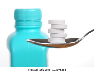 Antacid Tablets On A Spoon, A Bottle Of Antacid Blurred In The Background