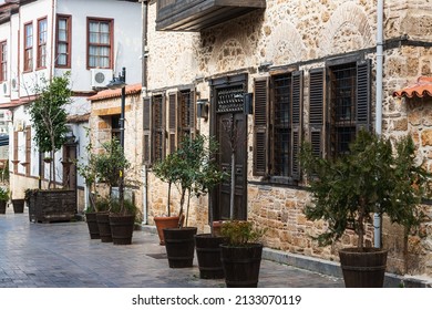 Antalya, Turkey – February 16 2022: 
 Close-up Of A Wooden Door And Flower Pots In A Brown  Stone Building