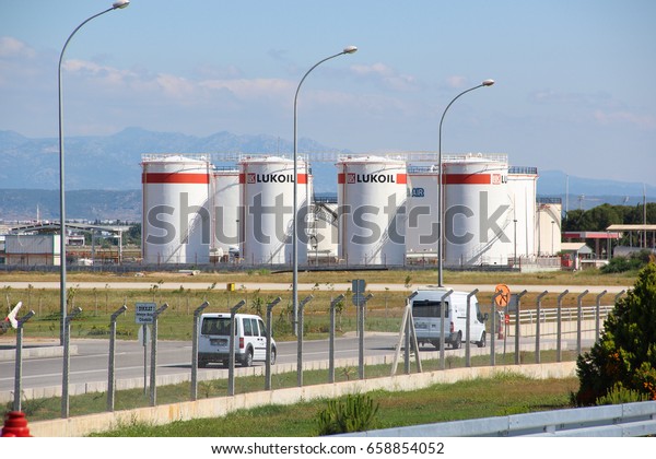 Antalya, Turkey - May 23\
2017: Tank oil storage company LUKOIL with gasoline near the city\
airport in the background of the road with cars, spring-summer,\
Sunny weather