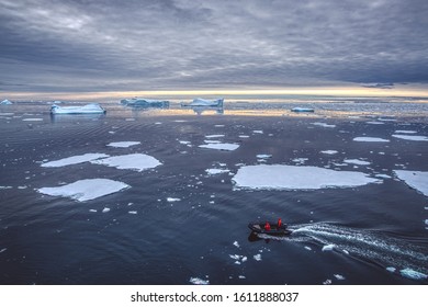 Antarctic Peninsula, Antarctica - January 2019: Zodiac boat making its way through the Antarctic sea with a floe of melting ice in the spring, against picturesque seascape and cloudy sky