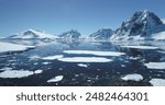 Antarctica ocean bay aerial landscape in sunny day. Melting ice floe on water surface, blue sky, snow covered mountains in background. Antarctic travel exploration. Discover beauty of South Pole