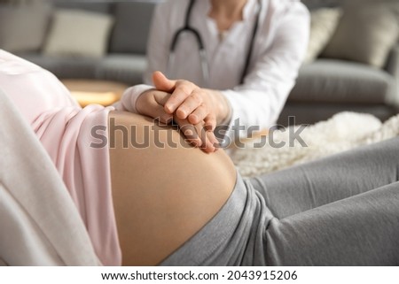 Antenatal care. Female doctor family therapist ob-gyn support comfort help young pregnant woman patient. Medic worker touching hand of expectant mother caressing her belly on checkup. Close up view