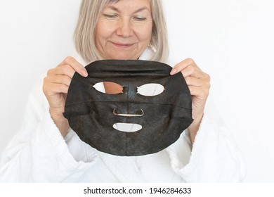 Anti Age Concept. Senior Woman Applies A Black Cosmetic Mask To Her Face. Mature Woman Face After Spa Treatment. Beauty Spa Treatment. Plastic Surgery Clinic, New Senior, Cosmetology