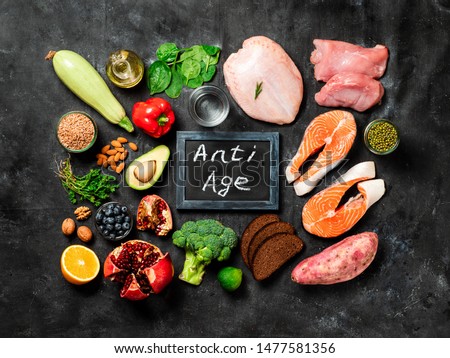 Anti Age menu and geriatric meal plan concept. Different food ingredients and chalkboard with Anti Age words on dark background. Top view or flat lay. Stock photo © 