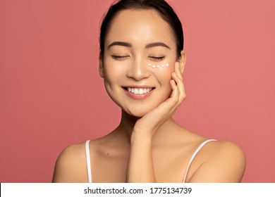 Anti Aging Eye Cream. Young Beautiful Model Posing Aginst Pink Background With Applyed Cream Under Her Eyes