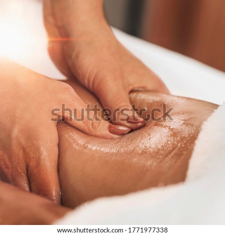 Anti cellulite massage of a female thigh. Hands applying pressure on hamstrings and improving circulation