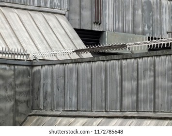 anti climb security rollers with barbed spikes on the walls and roof of a high security building with grey sloping surfaces