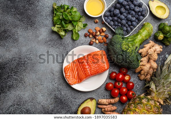 Anti inflammatory diet concept. Set of foods that\
help to reduce inflammation - plant based ingredients, fresh fruit,\
green vegetables. Healthy diet products, top view, stone background\
copy space