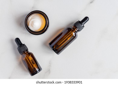 anti-aging collagen facial serum in dark glass bottle and face cream on marble background with copy space. Natural Organic Cosmetic Beauty Concept. - Powered by Shutterstock