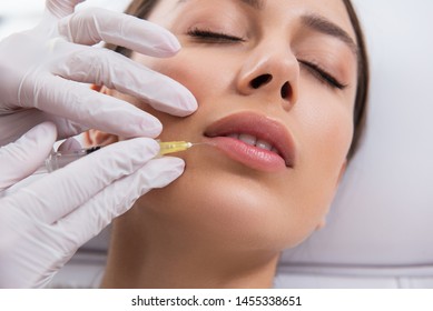 Anti-aging Face Treatment. Close Up Portrait Of Young Pretty Careful Woman Having Filler Procedure Of Her Plush Lips By Specialist