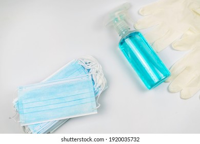 Antibacterial mask, hand sanitizer alcohol gel, and rubber gloves. New normal flat lay, on white background