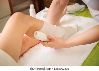 Anti-cellulite and cosmetologist STYX wraps procedure for legs in a spa center.