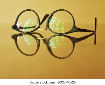 Anti-glare coating on eye glasses filters out short wavelength colors in the visible spectrum. Eye glasses on yellowish brown background. 
