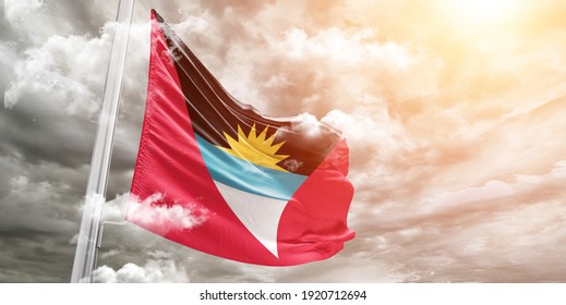 Antigua and Barbuda national flag cloth fabric waving on beautiful grey sky.